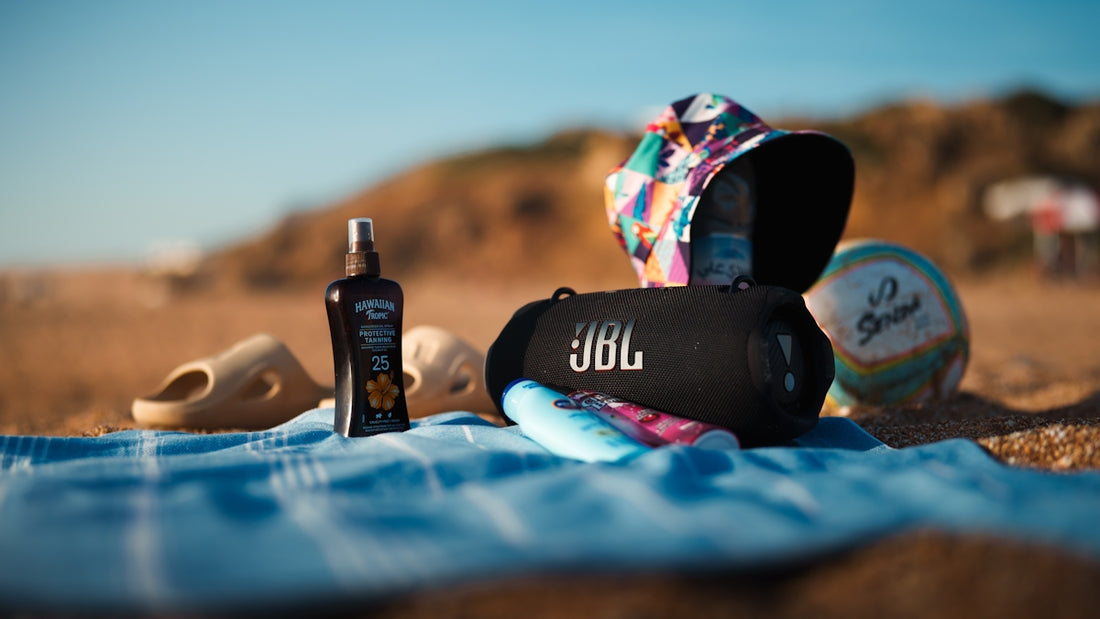 Beach essentials: jbl speaker, sunscreen, sandals, towel, and hat